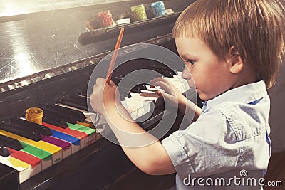 Young boy painting piano keys. Fine arts and music. Stock Photo