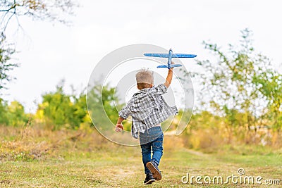 Young boy play with toy airplaine in hands. Happy Kid is playing in park outdoors Stock Photo