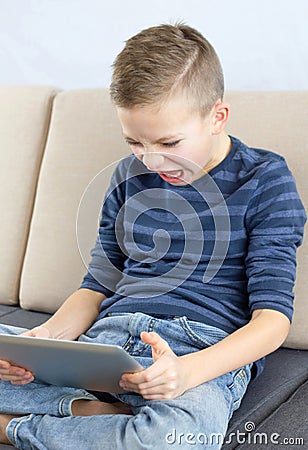 Young boy playing computer game on tablet with angry feeling Stock Photo