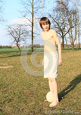 Young boy playing football barefoot Stock Photo