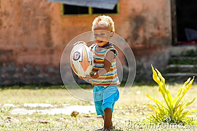 Young boy playing with rugby ball in Lavena village, Taveuni Isl Editorial Stock Photo