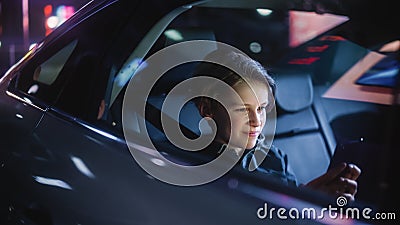 Young Boy is Sitting on Backseat of a Car, Commuting Home at Night. Passenger Watching Funny Stock Photo