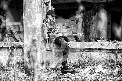 Young boy sitting on a crumbling building and using smarthphone Stock Photo
