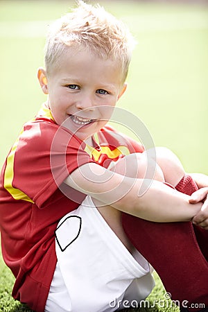 Young boy sitting on football field Stock Photo