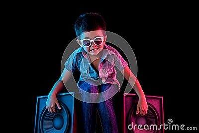 Young boy sitting on speakers looking cool with vivid red and blue colored lighting Stock Photo