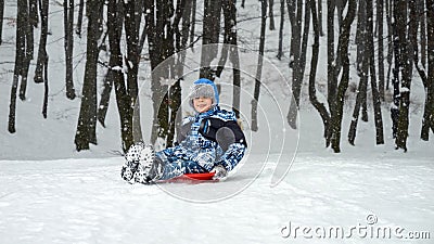 Young boy sledging down a snowy hill with excitement and exhilaration. The perfect scene to showcase the fun and joy of winter Stock Photo