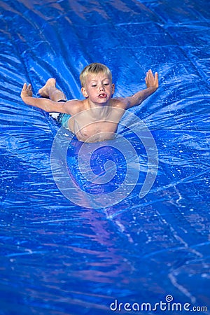 Young boy sliding down a slip and slide outdoors Stock Photo