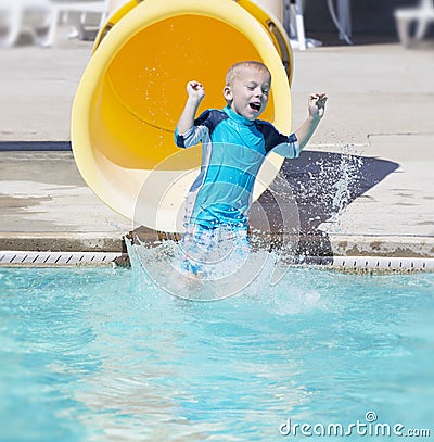 Young boy sliding out of a yellow water slide Stock Photo