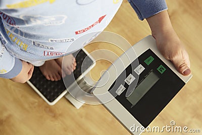 Young boy standing on digital scales cropped waist down Stock Photo