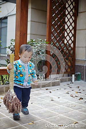 Young boy sweeping leaves Stock Photo