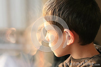 Young boy in thought with window reflection Stock Photo