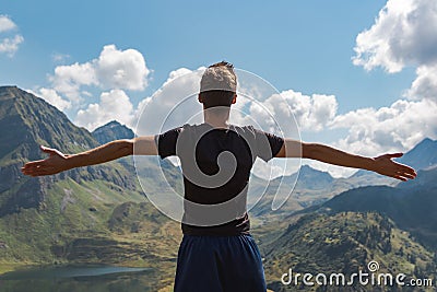 Young man`s arms raised enjoying freedom in the mountains during a sunny day Stock Photo