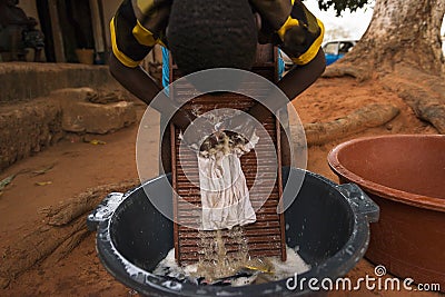 Young boy washing dirty clothes in a washing board and tub in the town of Nhacra in Guinea Bissau Editorial Stock Photo