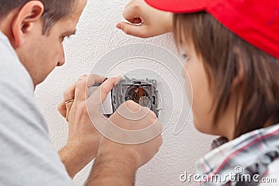 Young boy watches as his father installs an electrical wall sock Stock Photo