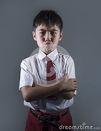 Young boy in school uniform feeling upset and angry looking unhappy and moody posing with folded arms on isolated background Stock Photo