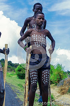 Young Boys of Benna Tribe with Traditional Body Painting on the Long Wooden Sticks posing for the picture Editorial Stock Photo