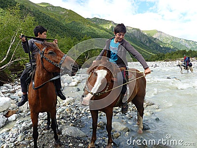 Young boys on horses in a river in Svanetie in Georgia. Editorial Stock Photo