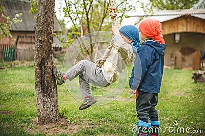 Young boys playing on the backyard - climbing rope near the tree. Editorial Stock Photo