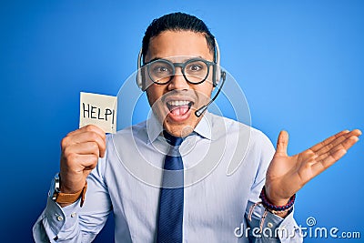 Young brazilian call center agent man overworked holding reminder paper with help message very happy and excited, winner Stock Photo