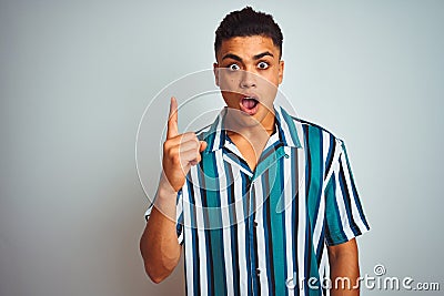 Young brazilian man wearing summer striped shirt standing over isolated white background pointing finger up with successful idea Stock Photo