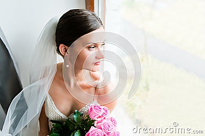 Young bride waits for groom near the window Stock Photo