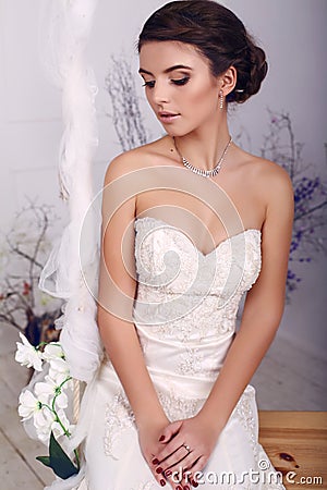 Young bride in wedding dress sitting on swing at studio Stock Photo