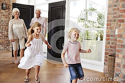 Young brother and sister arriving home with grandparents Stock Photo