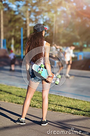 Young brown-haired woman with a skateboard in her hands on the background of a skateboarding platform Stock Photo