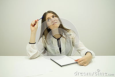 young brunette girl with flowing hair is sitting at a table with a notepad on the table Stock Photo