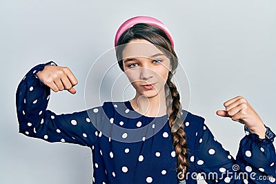 Young brunette girl wearing elegant look showing arms muscles smiling proud Stock Photo