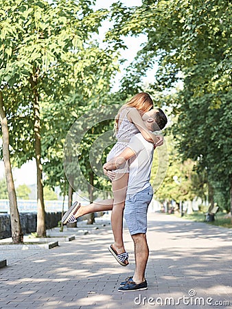Young brunette guy, spinning around with blond woman, held in his arms. Full-length picture of couple in love on romantic date. Stock Photo
