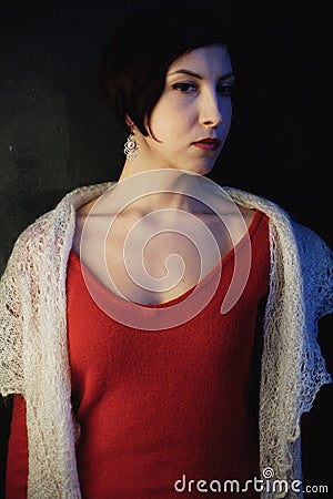 Young brunette with a short haircut in a red dress and a downy shawl Stock Photo