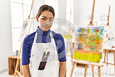 Young brunette woman at art studio looking sleepy and tired, exhausted for fatigue and hangover, lazy eyes in the morning Stock Photo