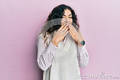 Young brunette woman with curly hair wearing casual clothes laughing and embarrassed giggle covering mouth with hands, gossip and Stock Photo