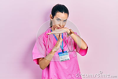 Young brunette woman wearing doctor uniform and stethoscope doing time out gesture with hands, frustrated and serious face Stock Photo