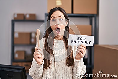 Young brunette woman working at eco friendly ecommerce afraid and shocked with surprise and amazed expression, fear and excited Stock Photo