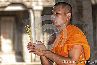 Young praying Buddhist monk in Angkor Wat, Cambodia Editorial Stock Photo