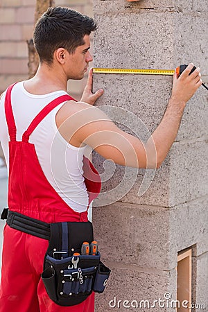 Young builder measuring wall Stock Photo