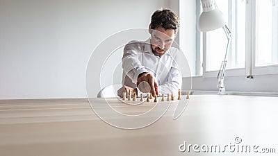 Young business executive positioning white chess pieces in a sensible structure Stock Photo