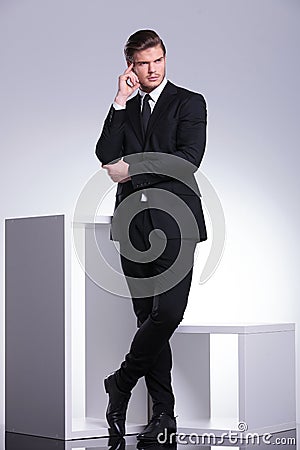 Young business man leaning on a white modern furniture piece Stock Photo