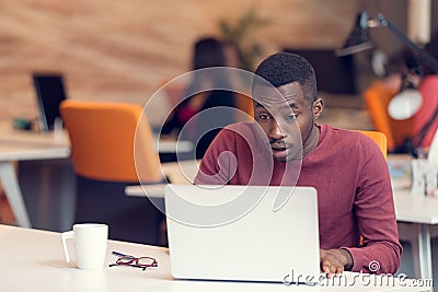 Young business man with a shocked expression working on a laptop Stock Photo