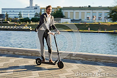 Young business man in a suit riding an electric scooter on a business meeting. Stock Photo