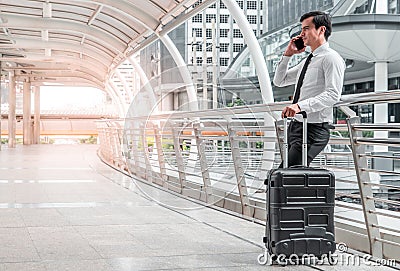 business man man on business trip standing with his luggage and making a call outside airport. Business traveler making Stock Photo