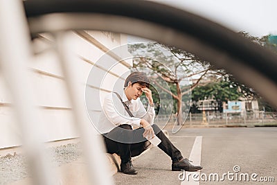 Young business man who lost job abandoned lost in depression sitting on ground street subway suffering emotional pain, thinking Stock Photo