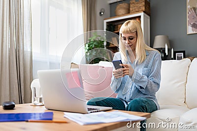 Young business woman freelance expatriate in smart casual working at home in home office using smartphone to check questions on Stock Photo