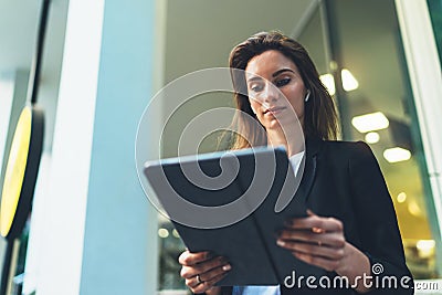 Young business woman reads financial news using tablet and Internet technology, elegant Manager in a business suit communicates Stock Photo