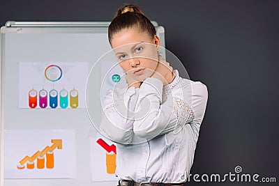 Young business woman squeezes her neck during a conference. Fatigue in business and pandemic Gray background Stock Photo