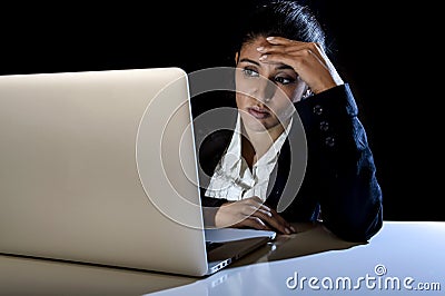 Young business woman or student girl working on laptop computer late at night bored and tired Stock Photo