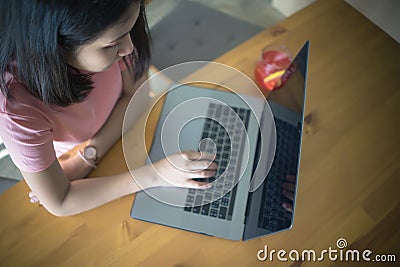 Young business woman using laptop computer working on wooden table with copy space. Asian girl typing on notebook in coffee shop, Stock Photo