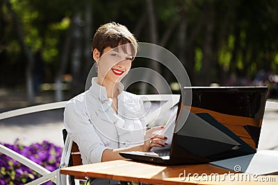 Young businesswoman using laptop at sidewalk cafe Stock Photo